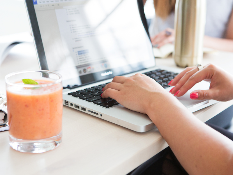 Joint Health Online Course with Antonia Cook at EssentiallyHealth.com Image of a woman sitting at her laptop typing with a glass of fresh juice next to her. Joint Health Online Course with Antonia Cook at EssentiallyHealth.com